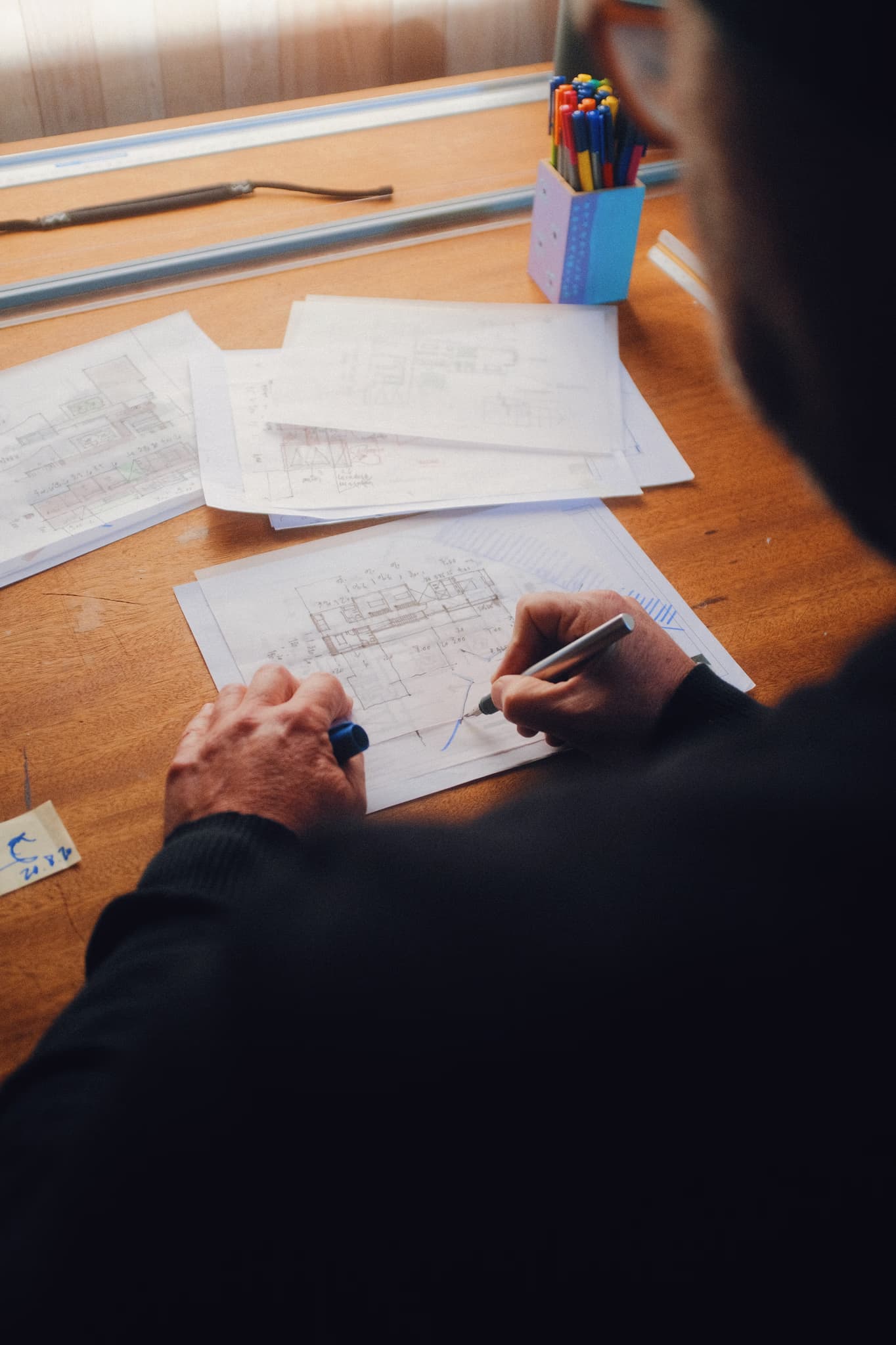 a photo of a desk with a lot of papers and a man with a pen working on those papers